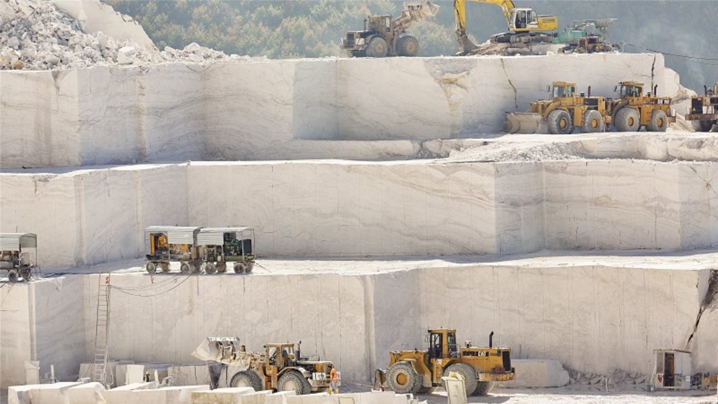 Terraced white marble quarry with heavy machinery